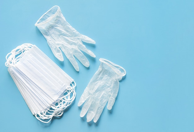 Face protective masks and vinyl gloves on blue table