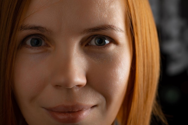 Photo the face of a redhaired woman of middle age 40 years old closeup she looks into the camera