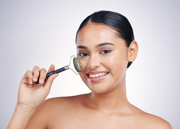 Face roller skin care and a woman in studio for beauty glow dermatology or natural cosmetic Portrait of happy female model with tools for facial massage and skincare benefits on a white background