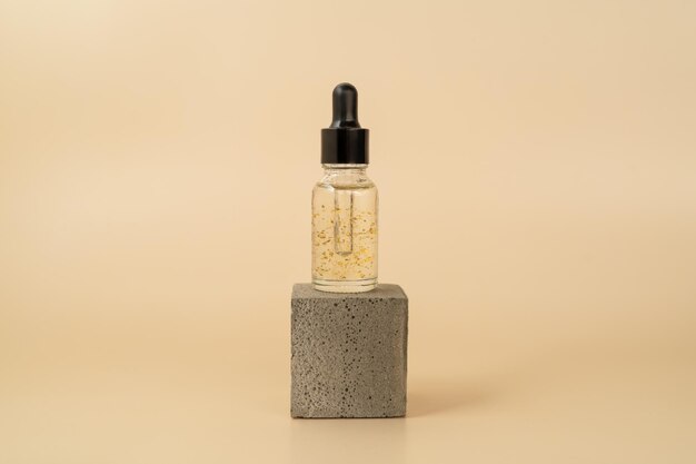 A face serum or essential oil with golden parts standing on a grey concrete podium