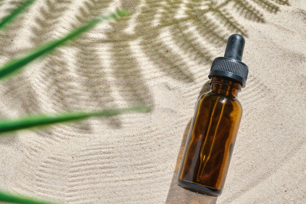 Siero viso di bottiglia di vetro con una pipetta su uno sfondo naturale con sabbia olio essenziale per idratare la pelle del corpo mockup di bellezza moda cosmetica bottiglia contagocce prodotto con il concetto di cura della pelle