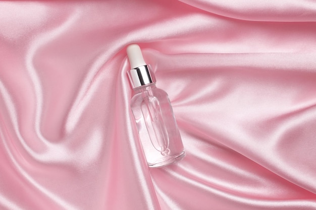 A face serum or natural essential oil lying on a pink fabric