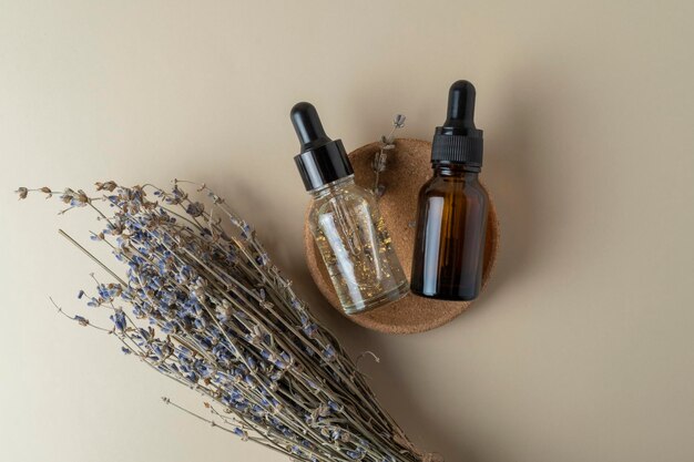 A face serum or oil in a brown dropper bottle standing on a beige table background with lavender flowers nearby