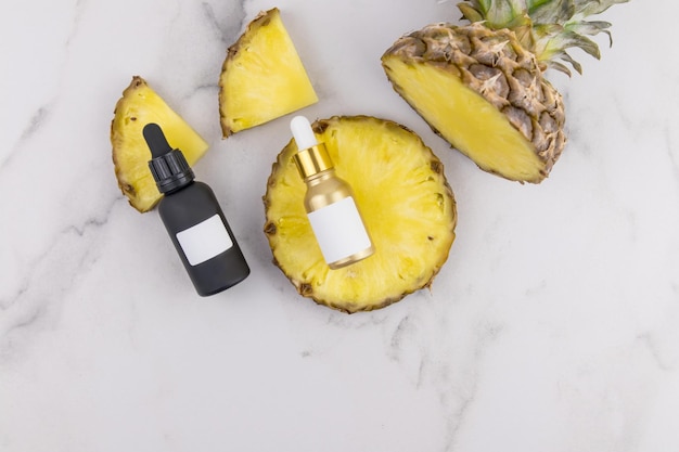 Face serum with pineapple extract or natural pineapple oil in cosmetic bottles with fresh juicy fruit slices.Unbranded mock-up.