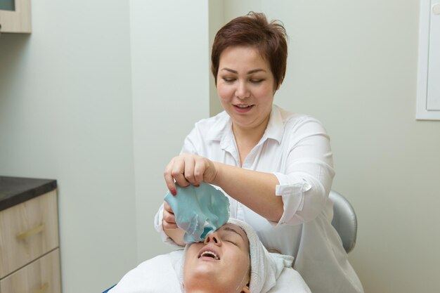 Face skin care Beautician applying beauty oil mask on face using brush In spa salon