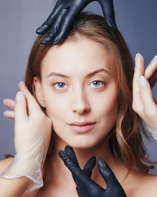 Face skin care concept. The girl's face surrounded by tender caring palms closeup.