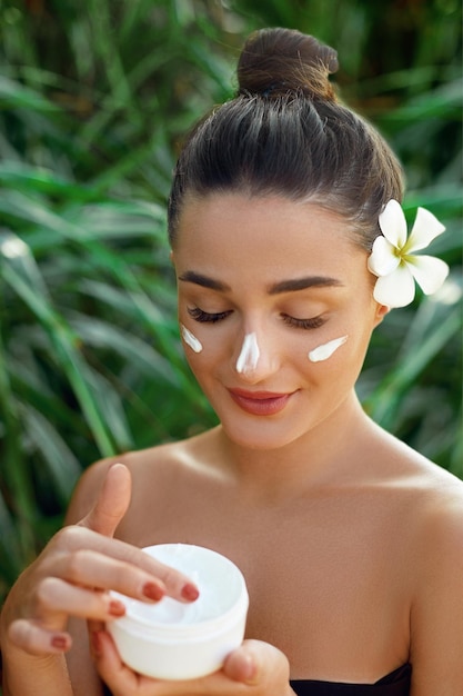 Face Skincare Beauty and Spa Concept Portrait of female holding moisturizing cream in her hand