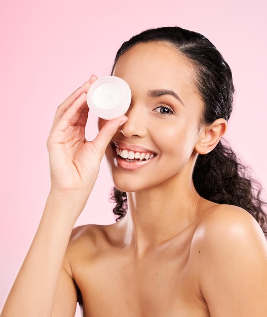 Face skincare and woman smile with cream container in studio isolated on a pink background Portrait beauty and happy model with moisturizer sunscreen cosmetic or dermatology product for wellness