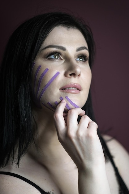 Photo face taping portrait of a beautiful woman with dark hair with teips on her face