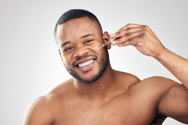 A face that is well hydrated is youthful Studio portrait of a handsome young man applying serum to his face with a dropper against a white background