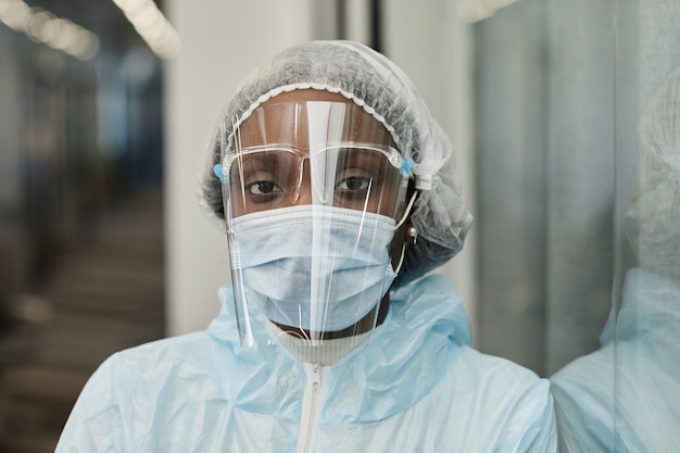 Face of tired black medical nurse in ppe suit medical mask and face shield protecting from coronavirus