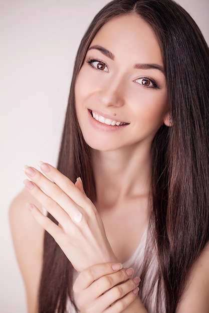 Face Treatment. Woman in Beauty Salon. Applying cosmetic cream. A beautiful young woman applying face moisturizer. Scine care of the face and hands