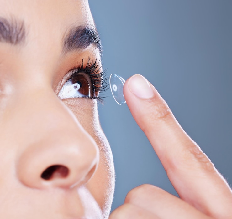 Photo face woman and eye care with contact lens iris and optometry with closeup in blue background female person ophthalmology and zoom for wellness and cosmetic in studio backdrop for sight or vision