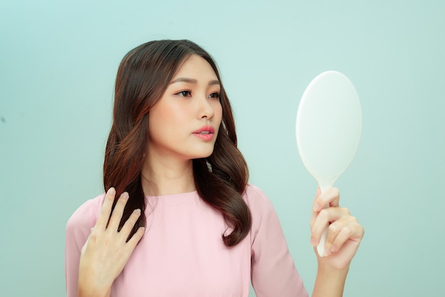 Face of young beautiful healthy woman looking in the mirror