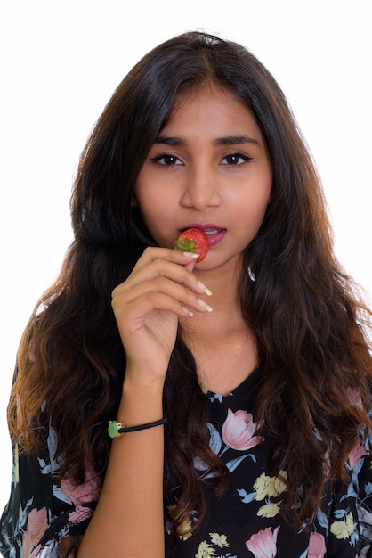 Лицо молодой красивой персидской женщины, едящей клубнику на белой стене
