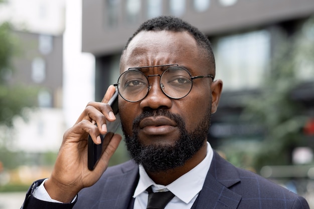Face of young elegant businessman in eyeglasses speaking on the phone