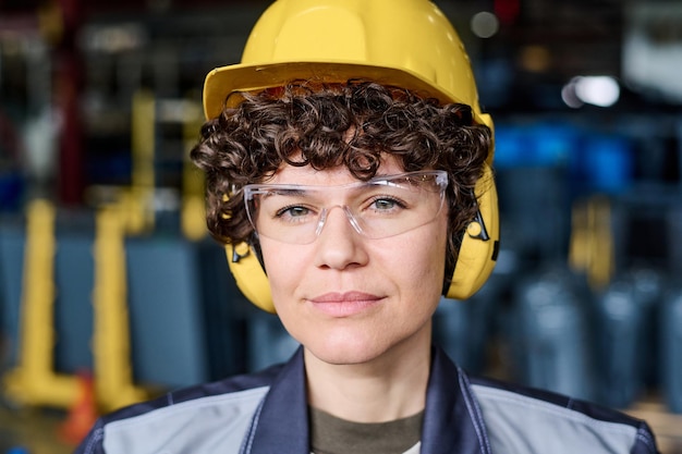 Face of young engineer in protective helmet eyeglasses and headphones