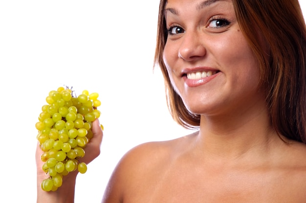 Foto il volto di un primo piano di una giovane ragazza, un grappolo di uva verde matura. il concetto di sana alimentazione e giovinezza.