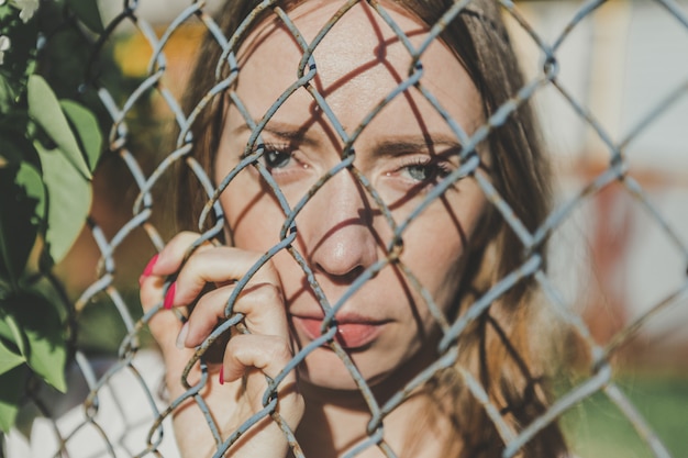 The face of a young girl behind a metal fence