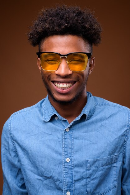 Face of young happy African man smiling on brown