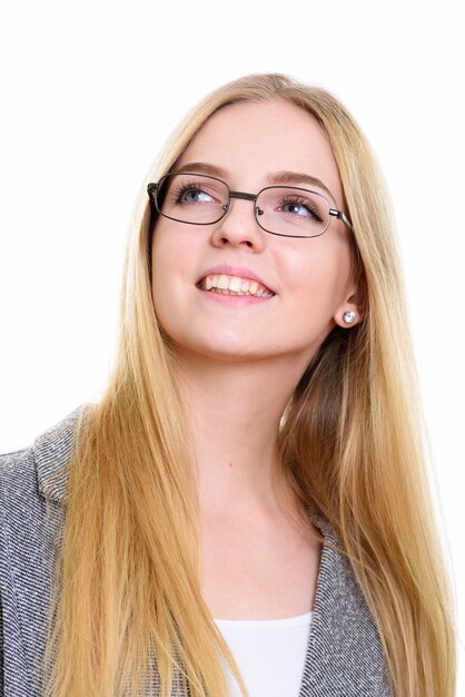 Face of young happy businesswoman smiling while thinking