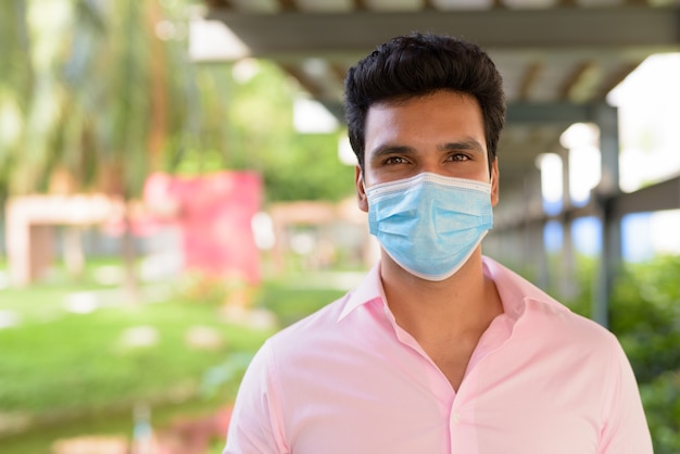 公園でマスクを身に着けている若いインド人実業家の顔