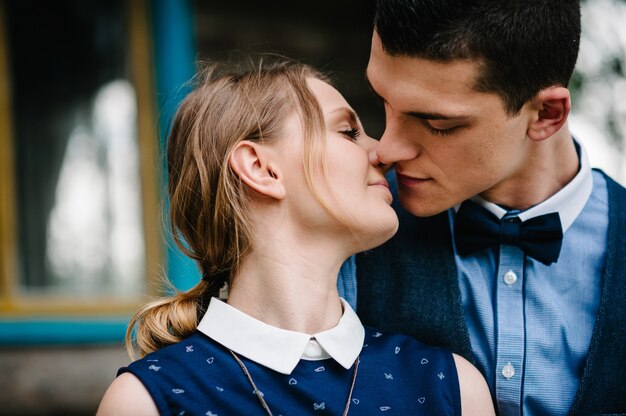 The face of young people. A young couple standing, hugging and kissing near a wooden old house