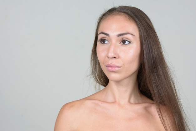 Face of young shirtless woman with brown hair thinking