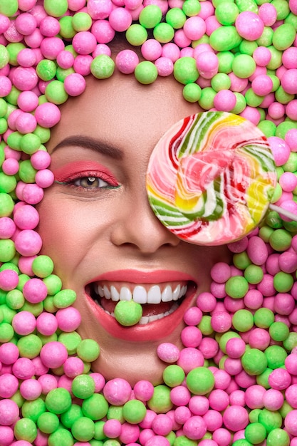 The face of a young woman among multi-colored sweets. Various sweets. Beautiful female smile