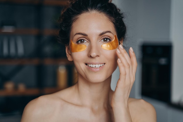 Face of young woman which applies collagen eye patches Portrait of happy girl doing spa procedures