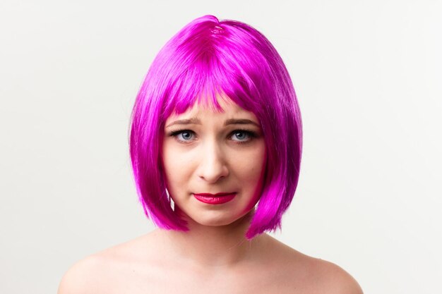 Face of a young woman with bright makeup on a pink background with gathered hair in a smooth ponytail