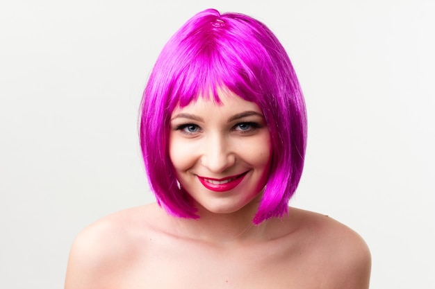 Face of a young woman with bright makeup on a pink background with gathered hair in a smooth ponytail