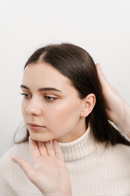 Facebuilding Doctor examines beauty face of woman Consultation with plastic surgeon on white background Cosmetic rejuvenating facial treatment