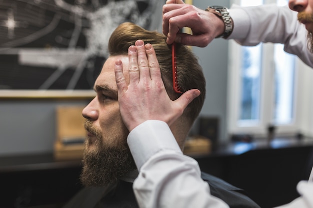 Foto barbiere senza volto che pettina i capelli del cliente