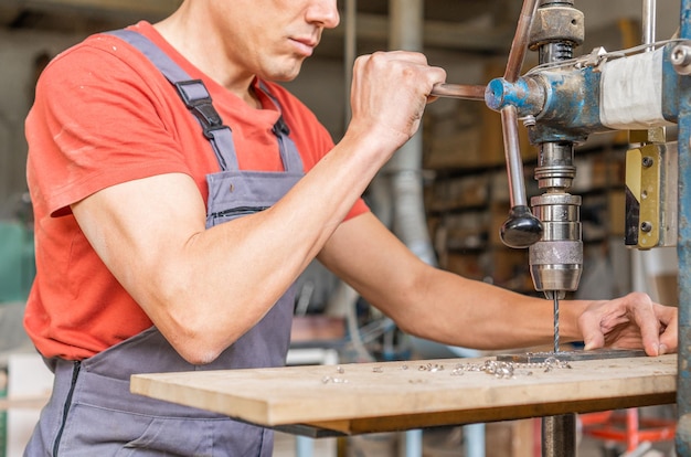 Безликий плотник сверлит сталь в профессиональной мастерской