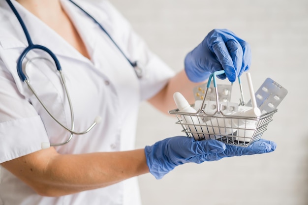 Безликая женщина-врач держит мини-корзину с лекарствами