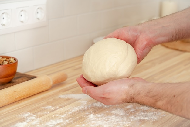 Faceless man kneading dough on kitchen table at home,