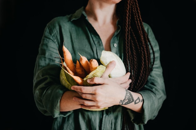 Foto ritratto senza volto di una donna vegana che tiene in mano delle verdure veganismo vegetarianismo dieta a base di piante