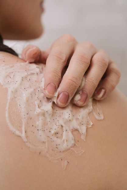 Faceless shot of woman using narutal scrub on her shoulder in the shower