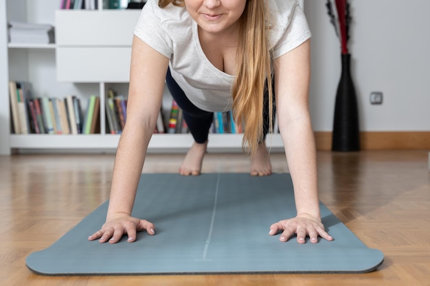 Faceless woman making pushups on a mat at home