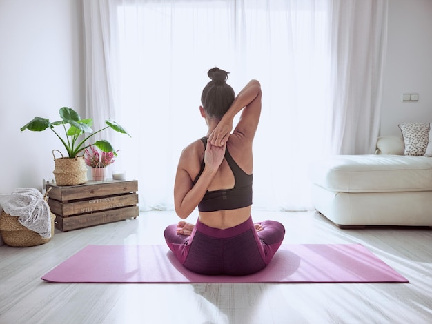 Faceless woman practicing cow face asana