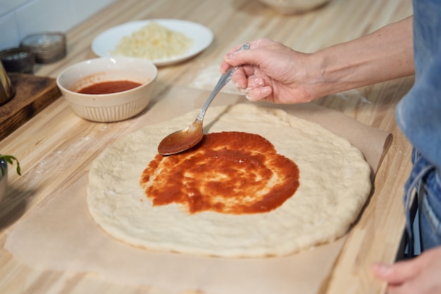 Faceless woman topping Rustic Italian homemade Pizza Dough margherita. Homemade food