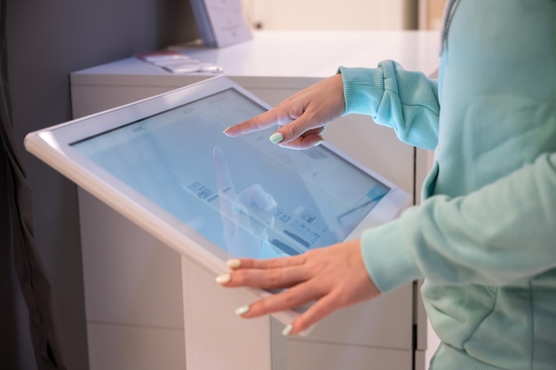 faceless woman touching the screen of a selfservice device in a store device store navigator self purchase