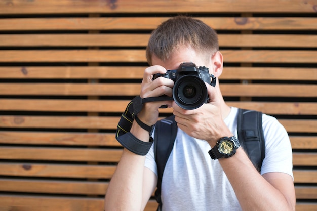 Faceless young man with digital SLR camera on the wooden backgroung