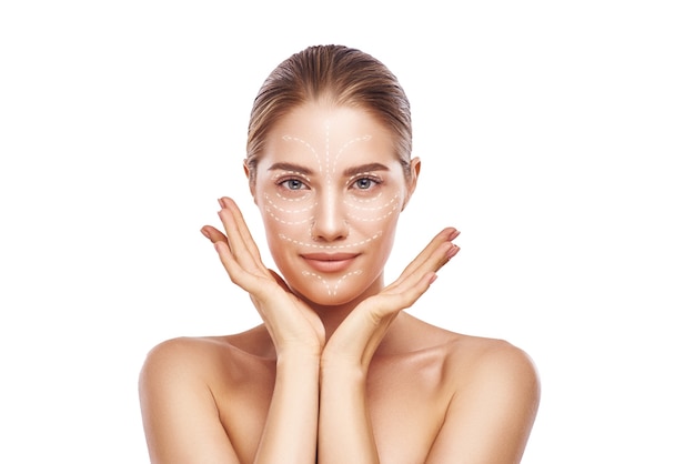 Facelift. Portret van een prachtige en jonge vrouw met een frisse, schone huid en pijlen over haar gezicht. Geïsoleerd op een witte achtergrond. Cosmetische geneeskunde. Plastische chirurgie. Anti-aging behandeling.