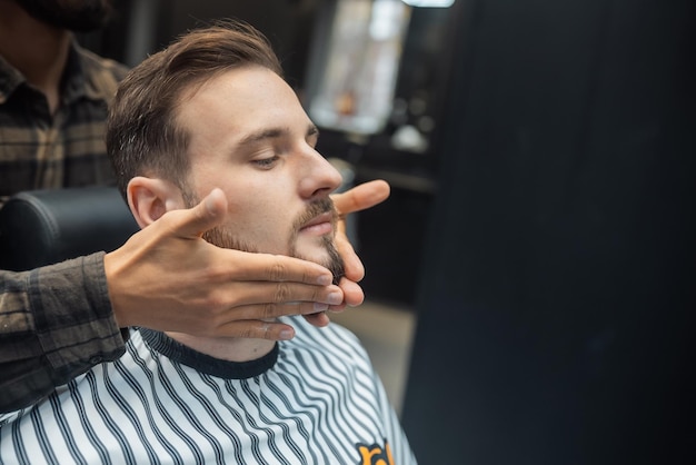 Lozione per l'applicazione del viso dopo la rasatura nel negozio di barbiere le mani del maestro si chiudono