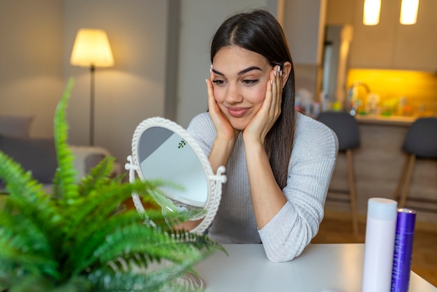 Facial Beauty. Portrait Of Sexy Young Woman With Fresh Healthy Skin Looking In Mirror Indoors