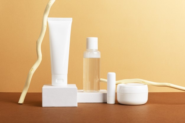 Facial and body care cosmetics bottles composition on brown background