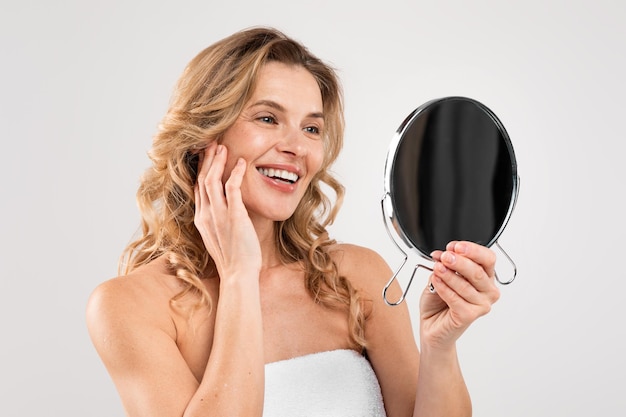 Facial Care Attractive Middle Aged Woman Looking At Mirror And Touching Face