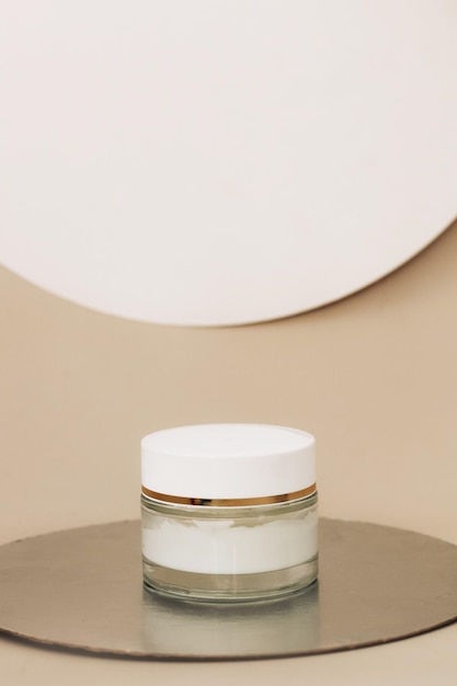 Facial care cream in a glass jar on a beige background